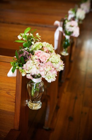 pink-and-green-flowers-in-glass-vase-tied-to-chapel-aisle