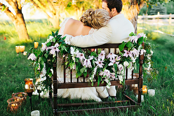 Bride and Groom on Bench With White Flower and Greenery Garland1