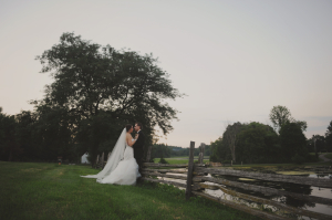 Bride and Groom Leaning on Wood Fence
