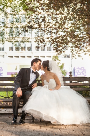 Bride and Groom Kissing on Park Bench