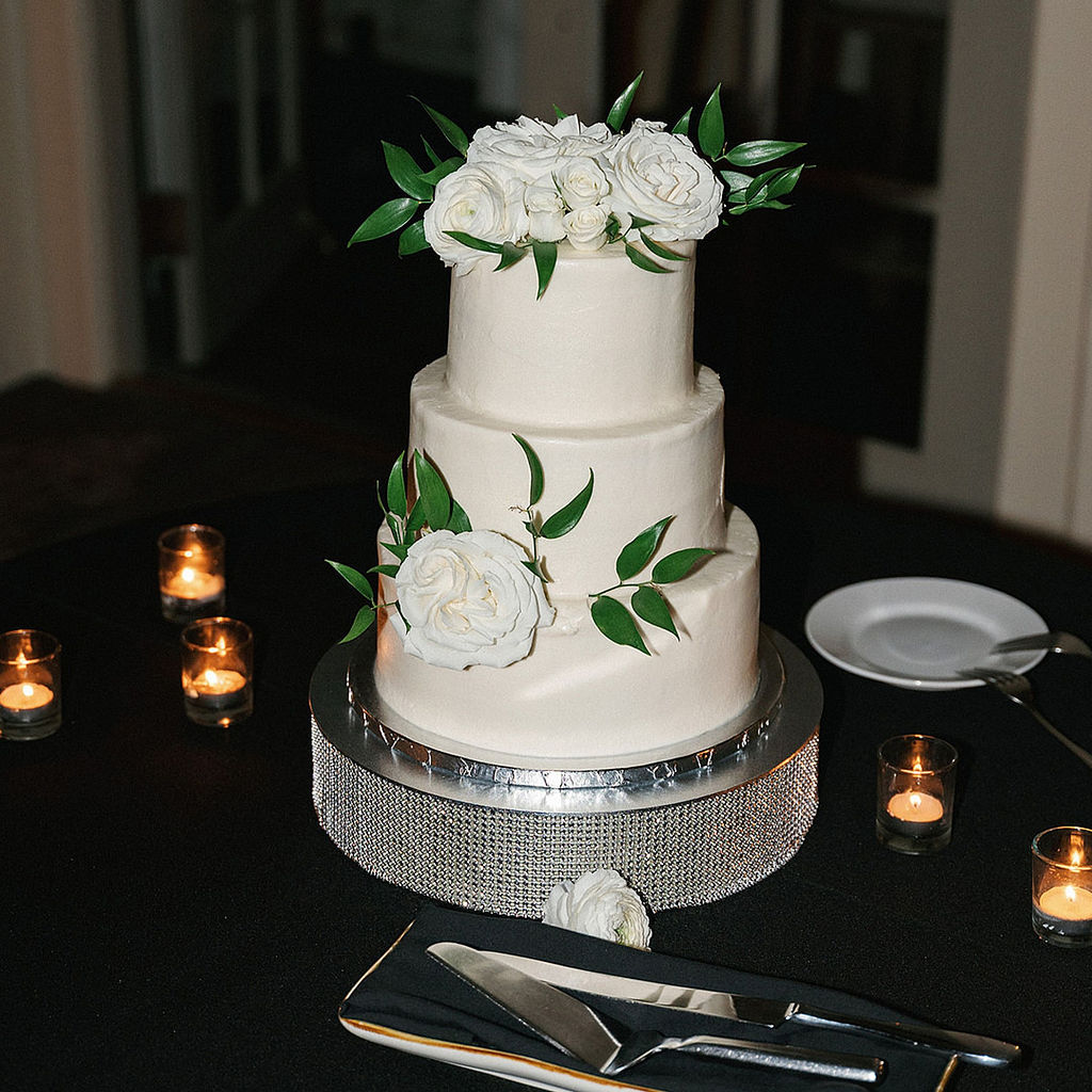 3 layer wedding cake that is white with flowers and greenery