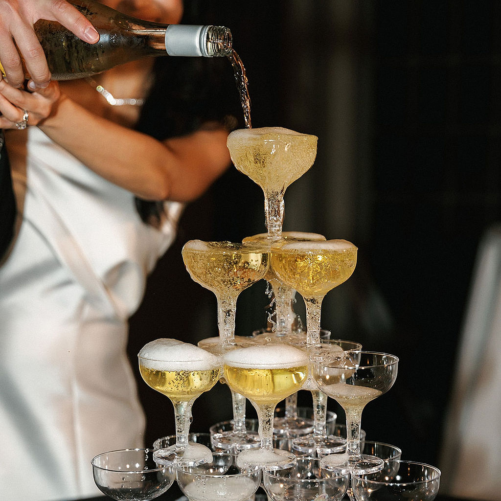 Bride and groom pouring champagne into a coupe tower together at Marbella Country Club